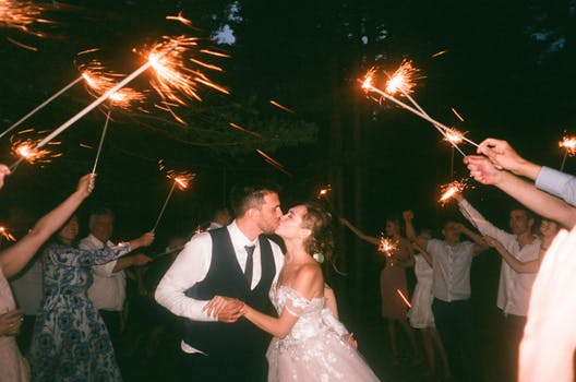Just married couple kiss as they dance their first dance to Scotland wedding bands with guests holding sparklers in a circle around them.